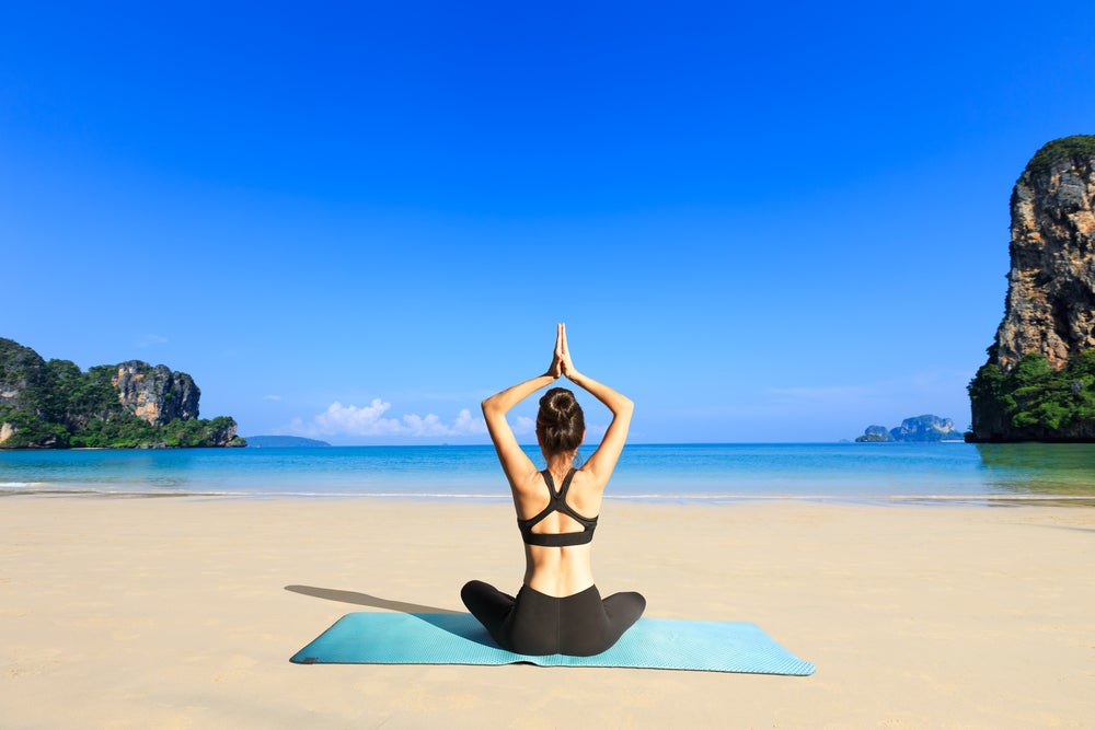 Premium Photo | Sporty beautiful young woman practicing yoga, sitting in  easy pleasant pose. meditation on the beach.