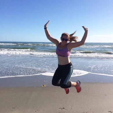 Runner woman running on beach with watch and sports bra top