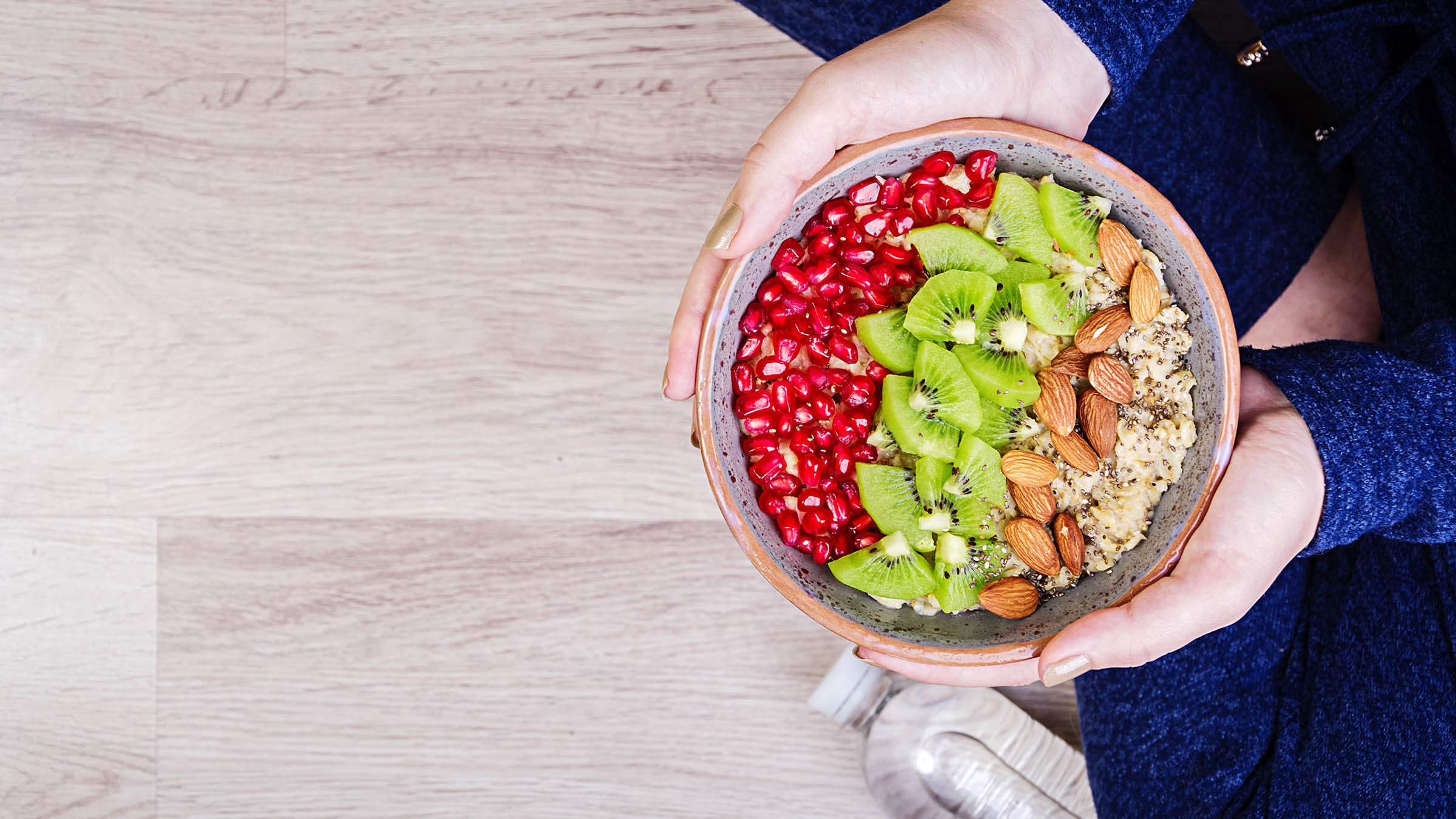 woman holding bowl of oatmeal with assorted toppings