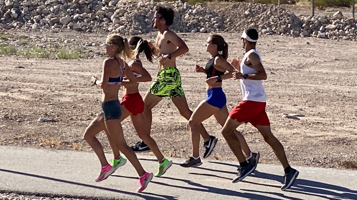 Group of runners training in hot weather on road.