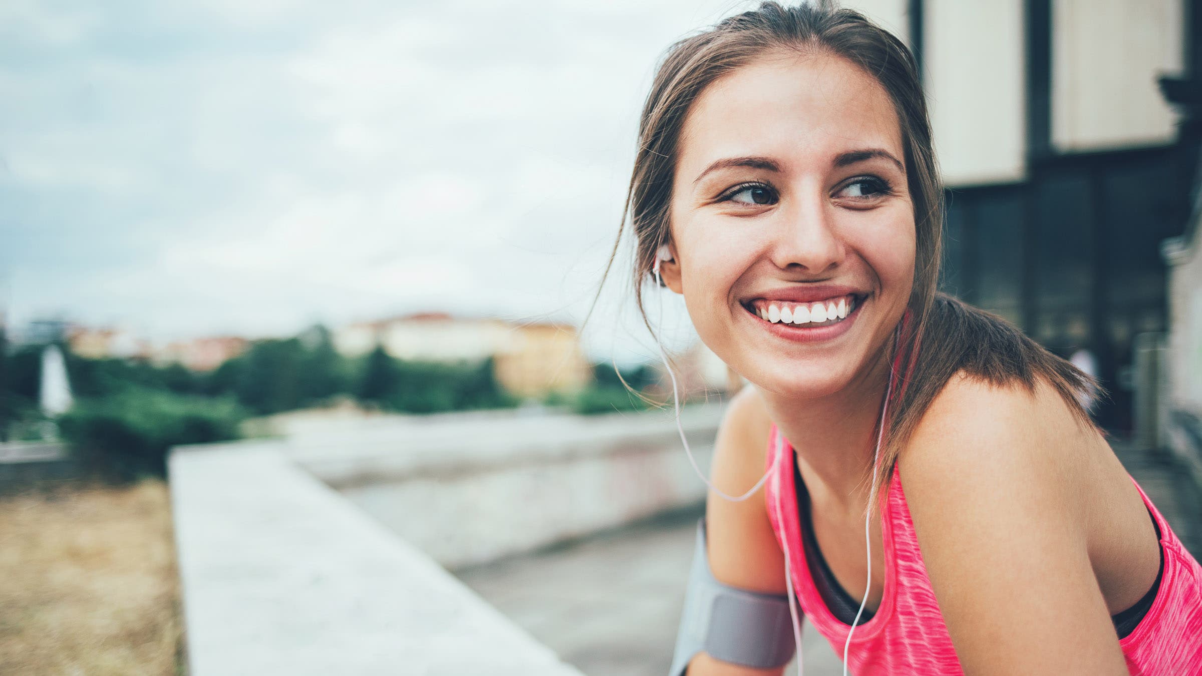 Woman in sports wear with headphones, sitting and resting.