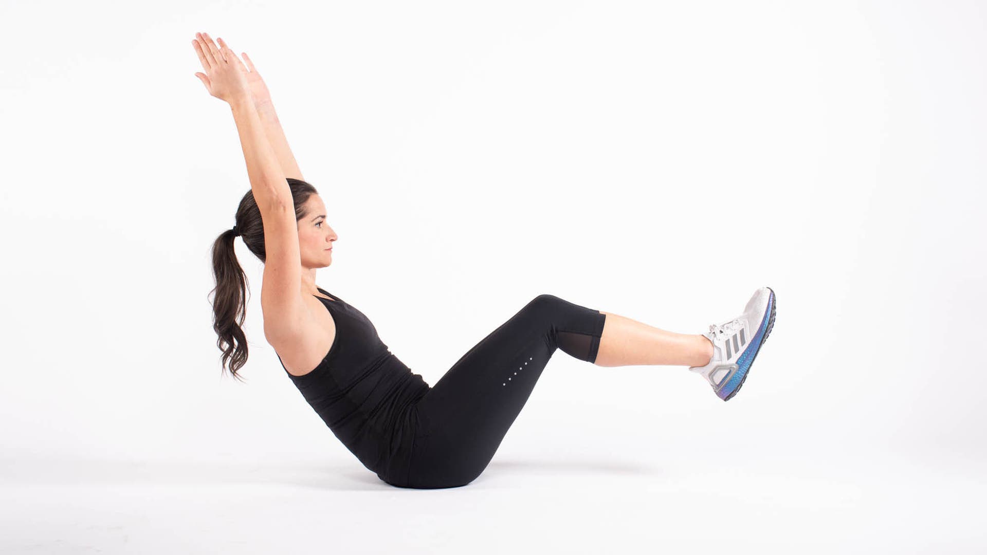 Woman doing isometric boat pose with arms and leg lifted