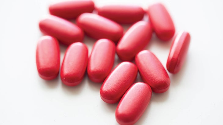 Red iron supplement pills on white background