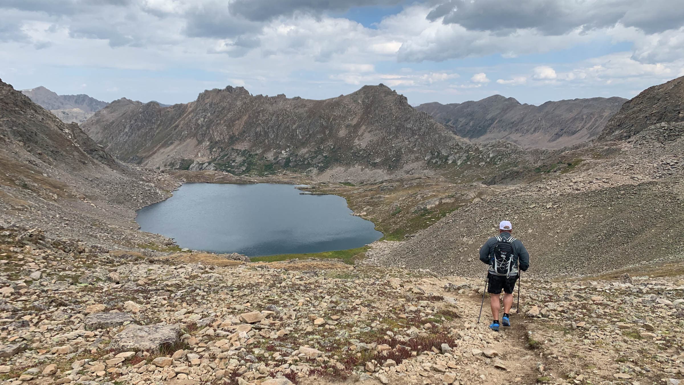 Person hiking toward an alpine lake in the mountains