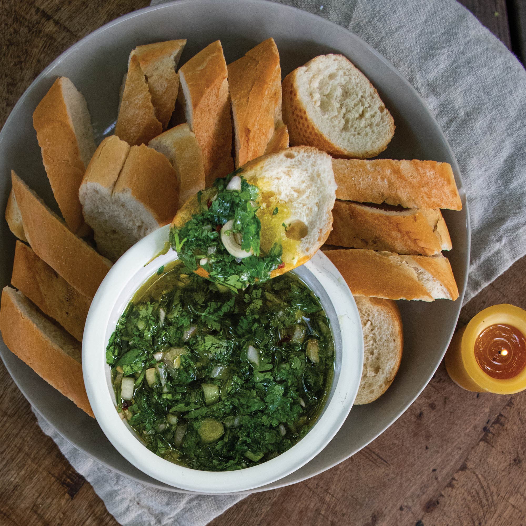 Chimichurri oil dip recipe in bowl with sliced bread