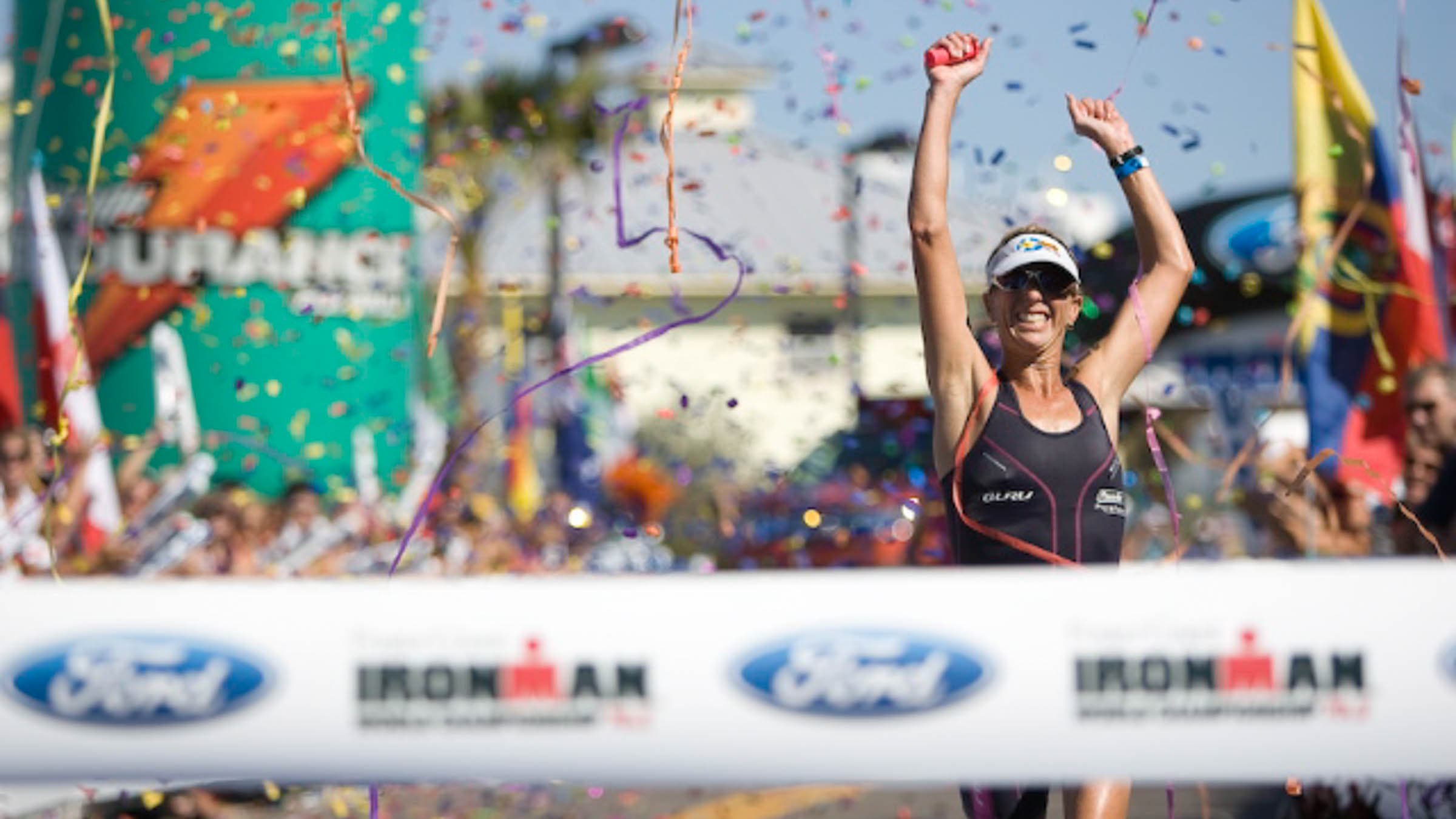 Dr. Joanna Zeiger runs triumphantly to the Ironman finish tape, arms raised