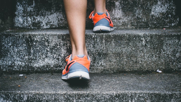 Rear shot of orange Nikes ascending a concrete staircase