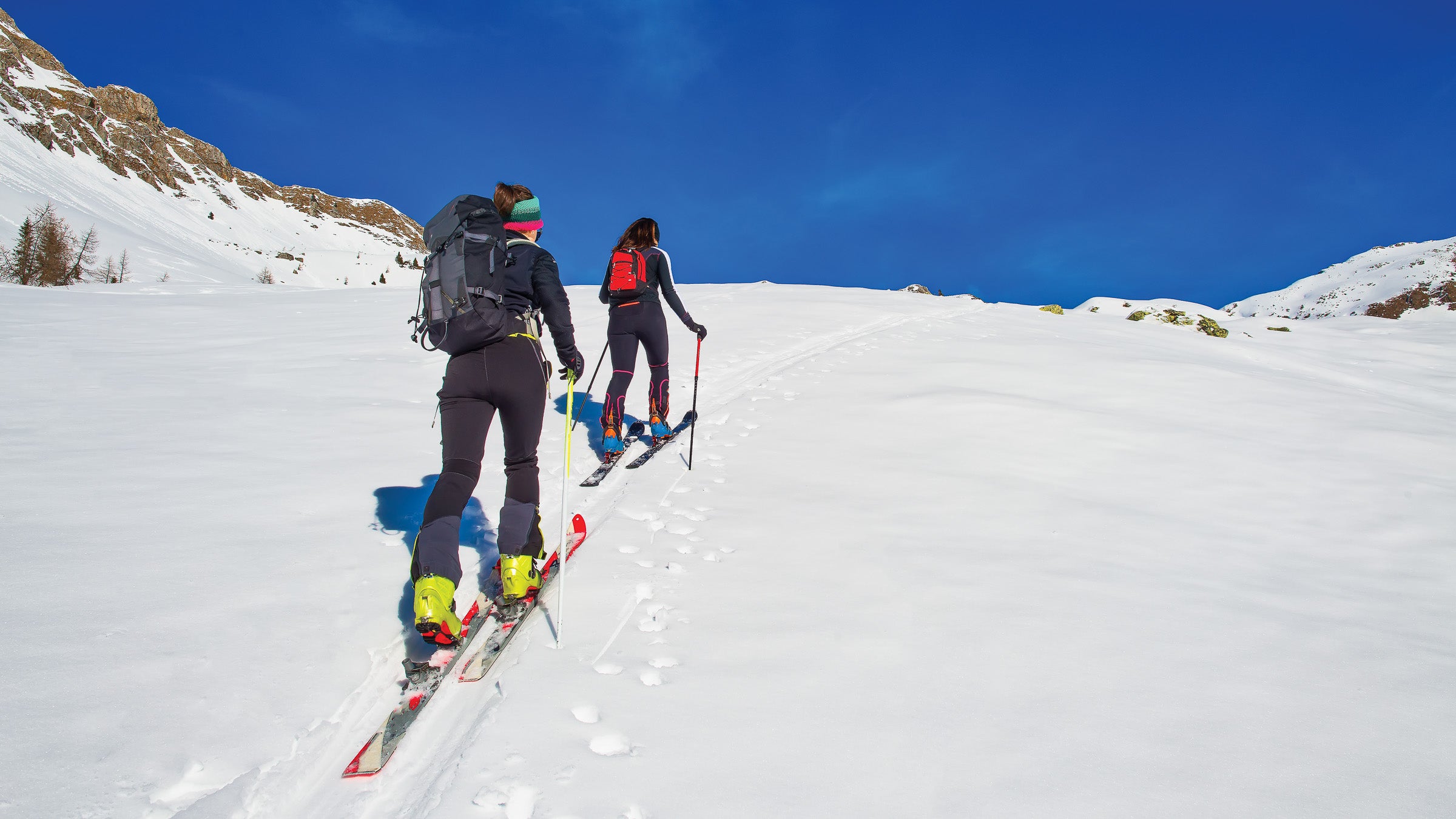 Two women ski mountaineering uphill