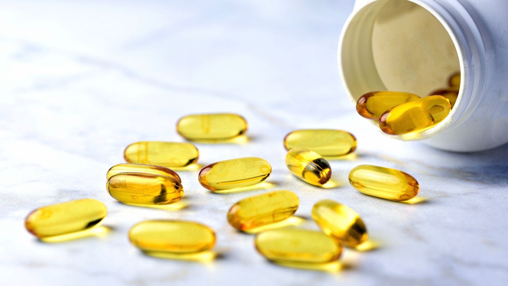 Bottle of yellow fish oil pills on table