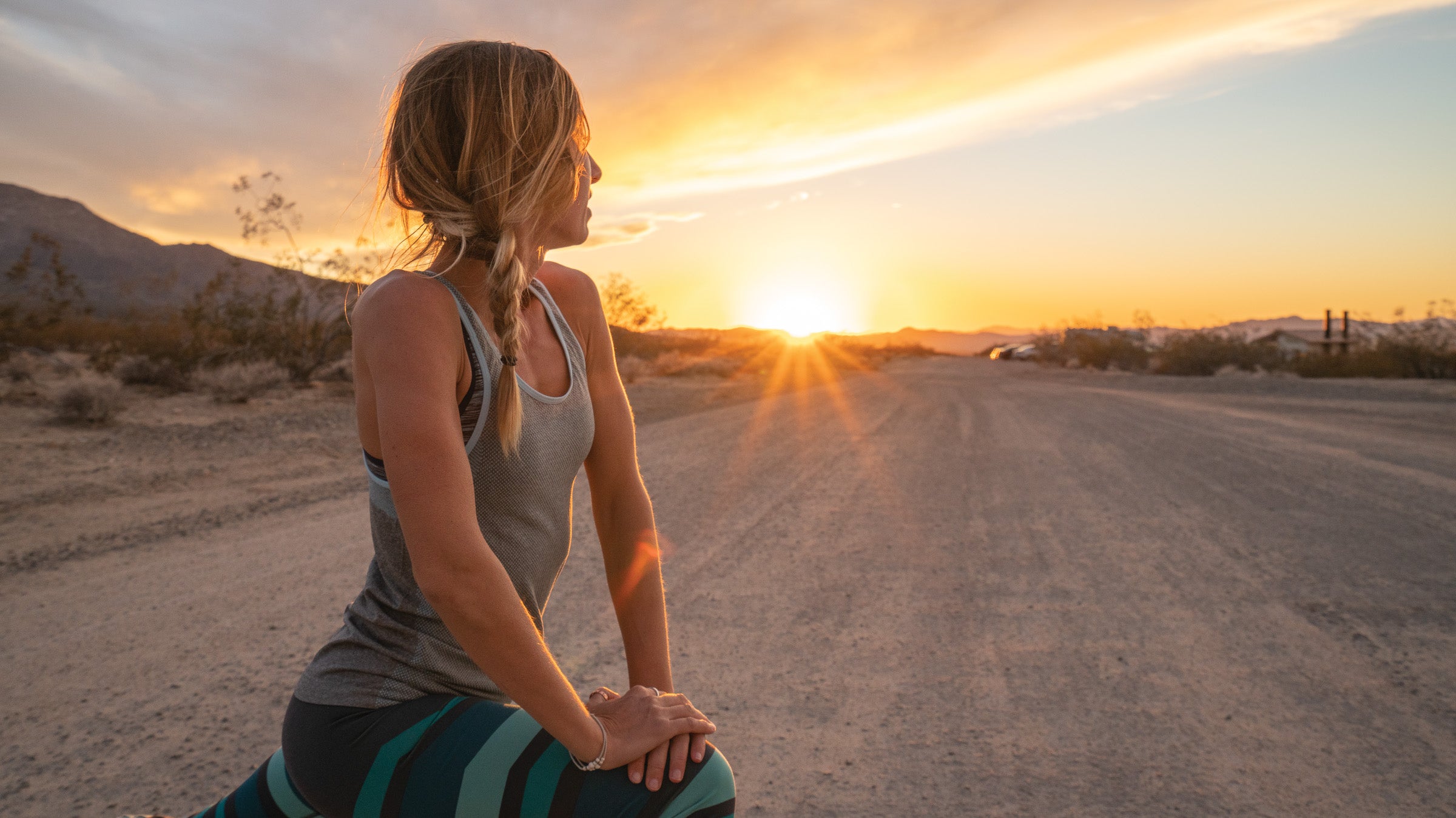 Woman stretching in a lunge after running at sunset.