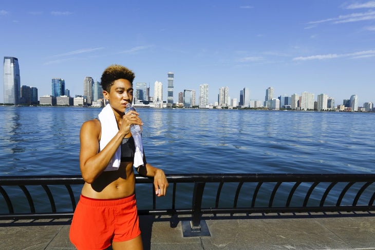 Mixed race woman drinking water during half marathon training