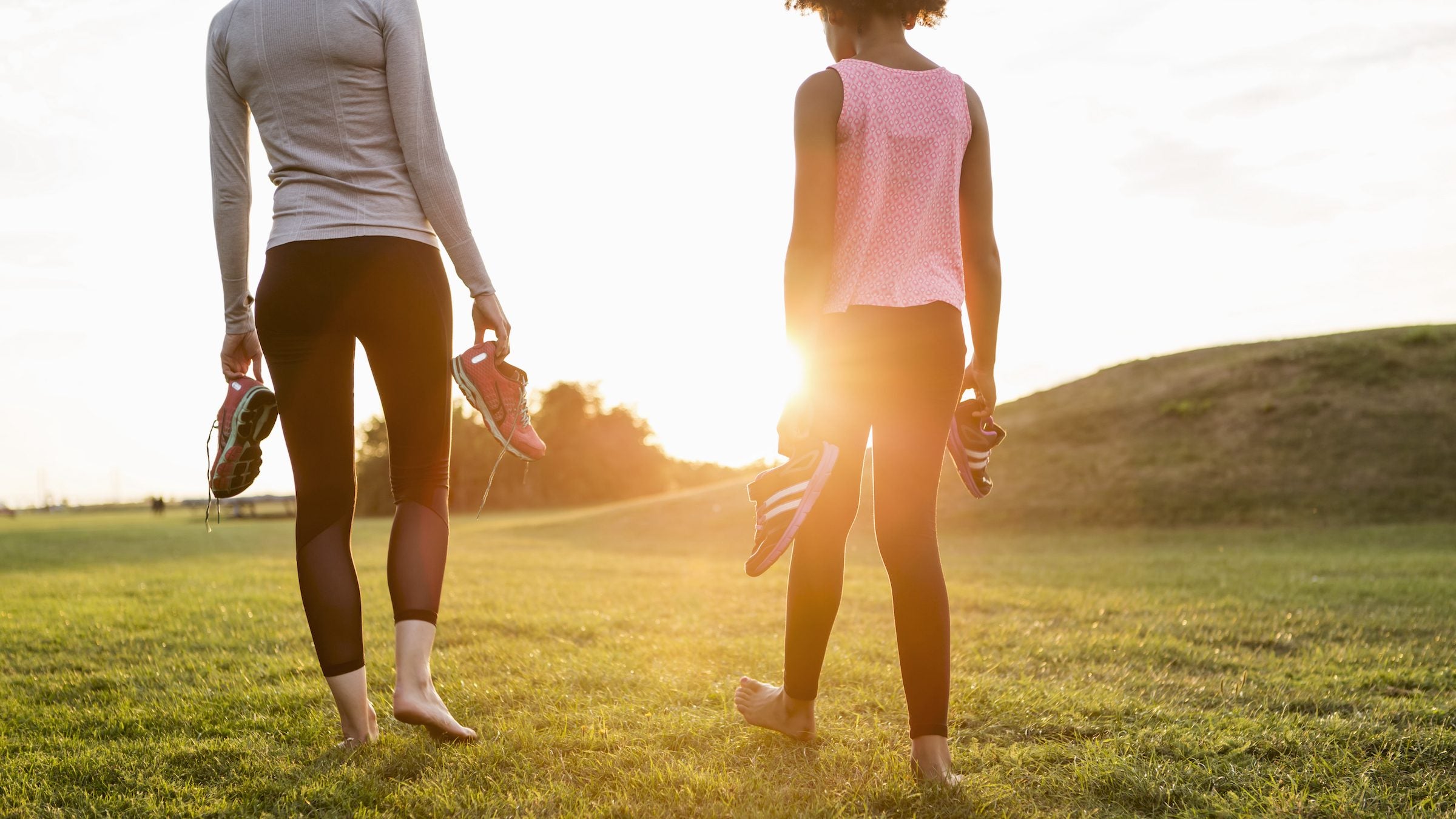 Woman and daughter practicing "grounding" with bare feet in the grass