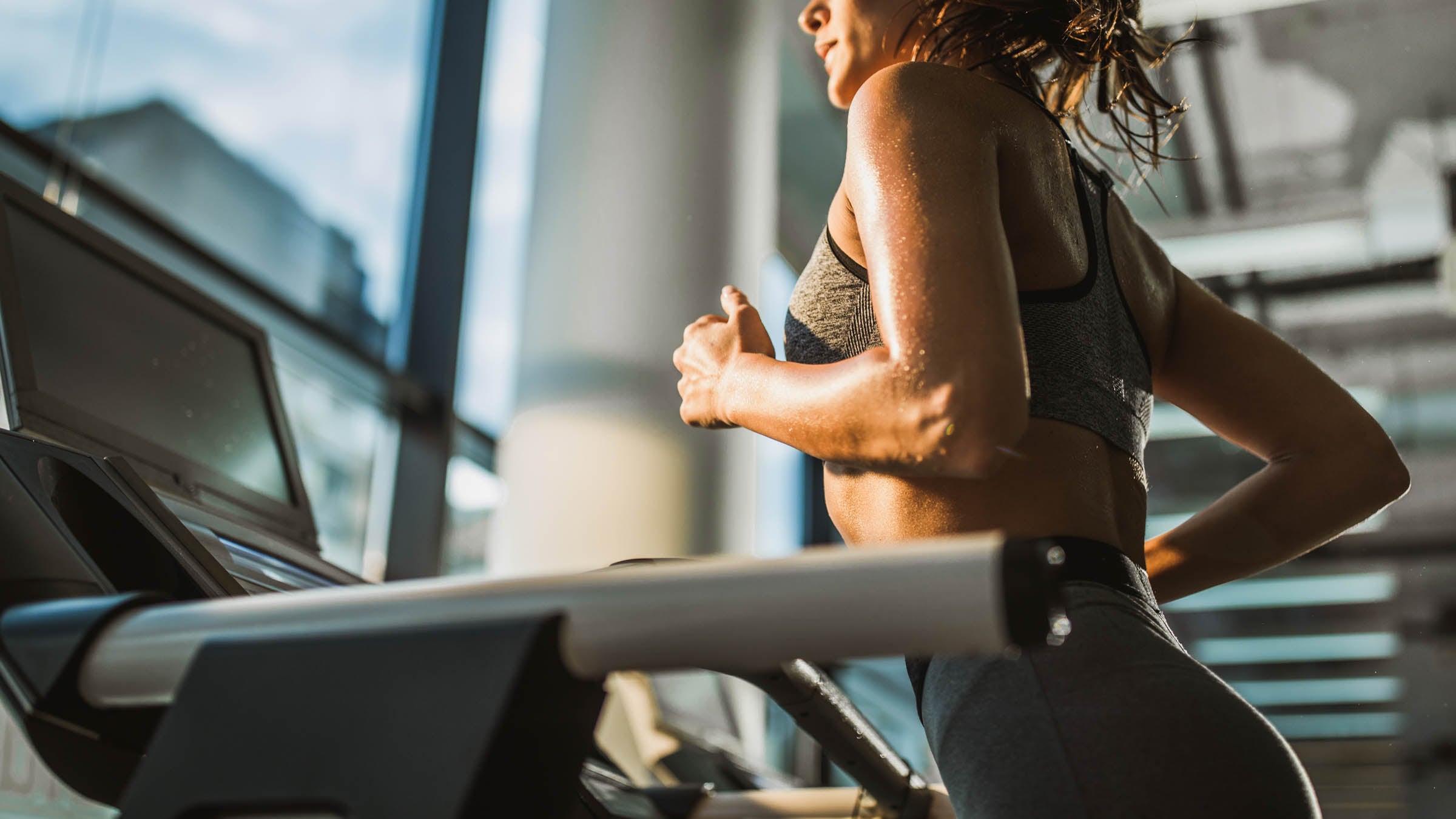 Unrecognizable athletic woman running on treadmill in a health club.