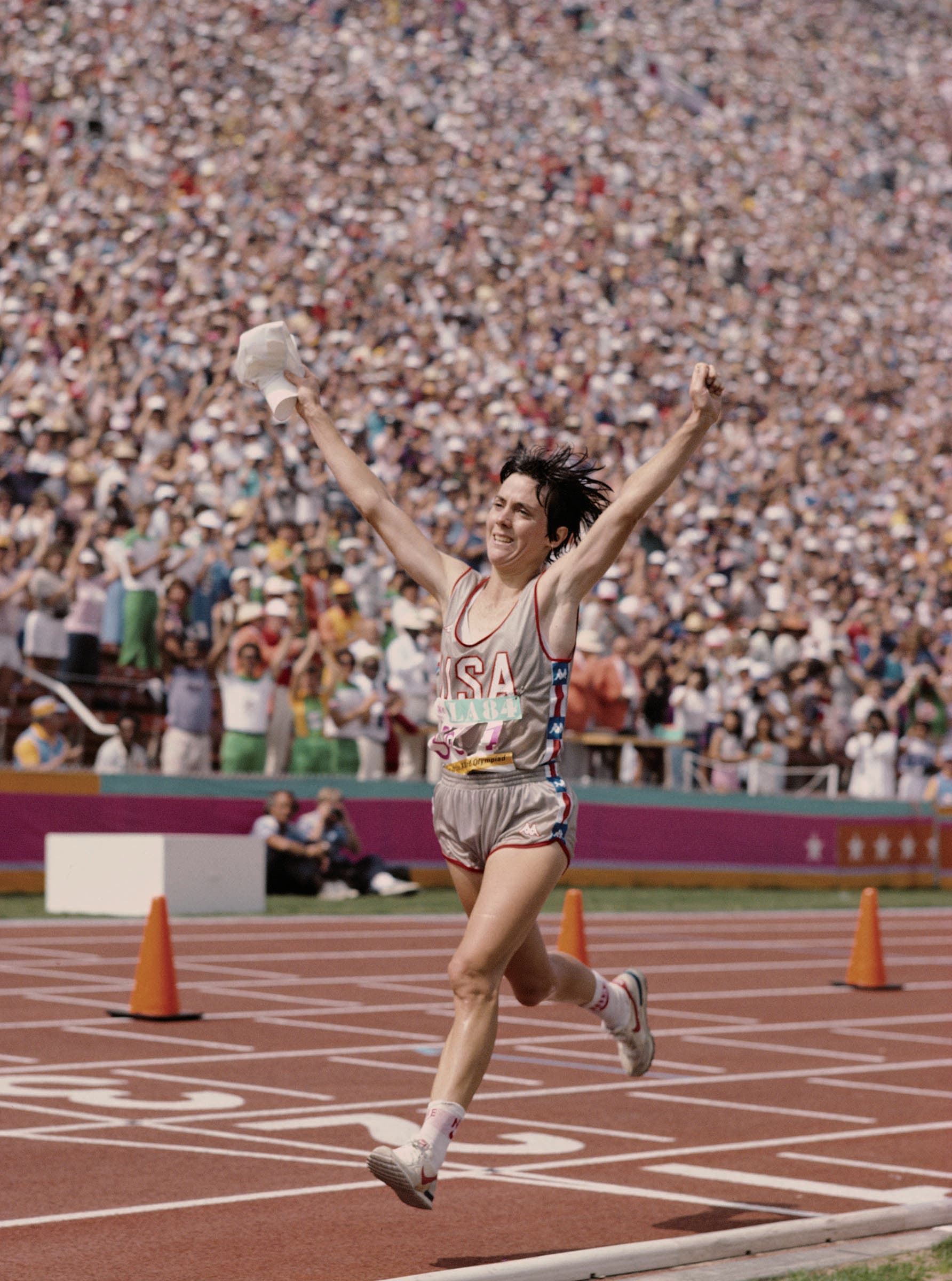 Joan Benoit Samuelson crossing finish line with arms raised