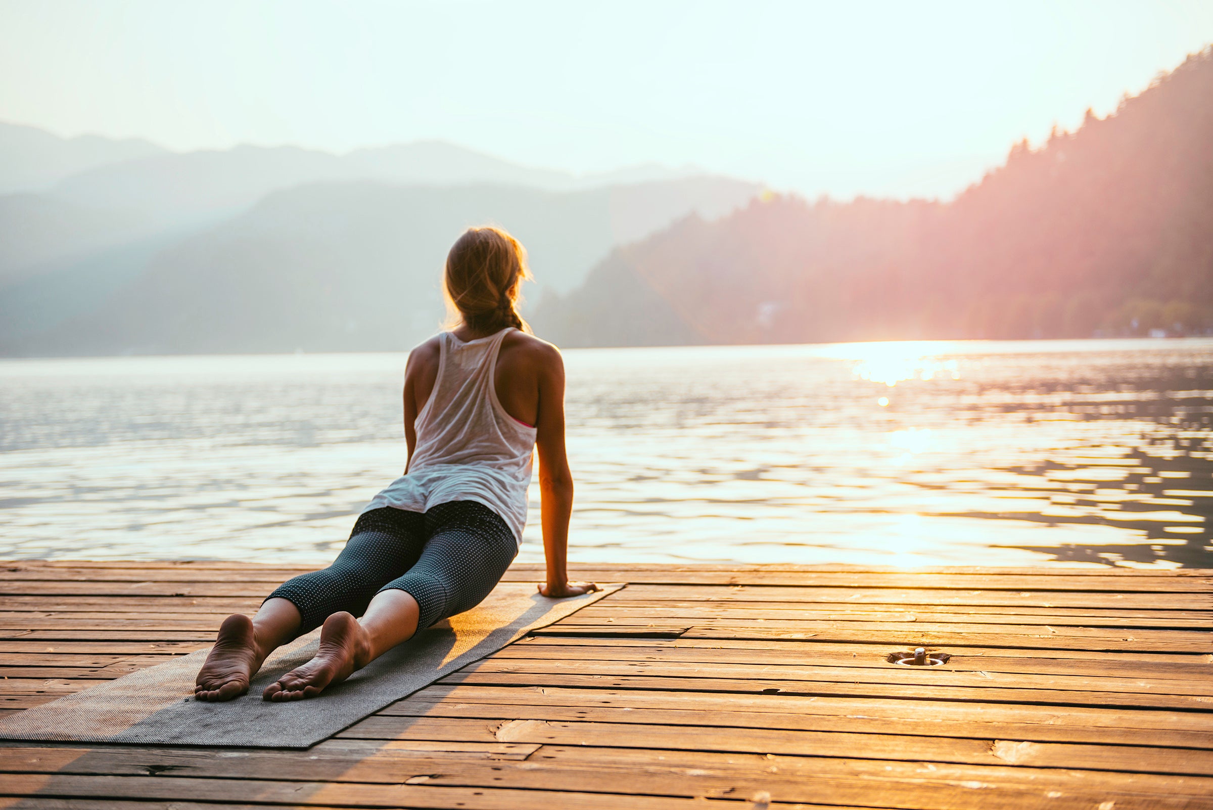 woman practicing Yoga by the lake - Sun salutation series - Upward facing dog