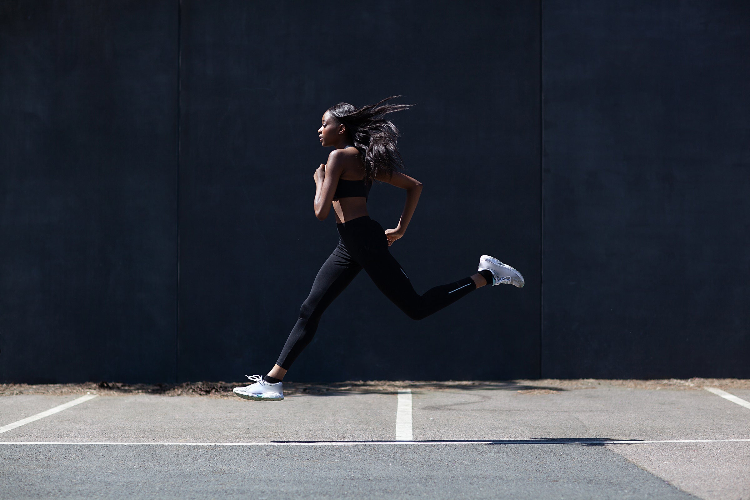 Young black woman running on the road