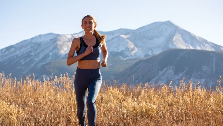 Sara Hall running through grass in front of mountains