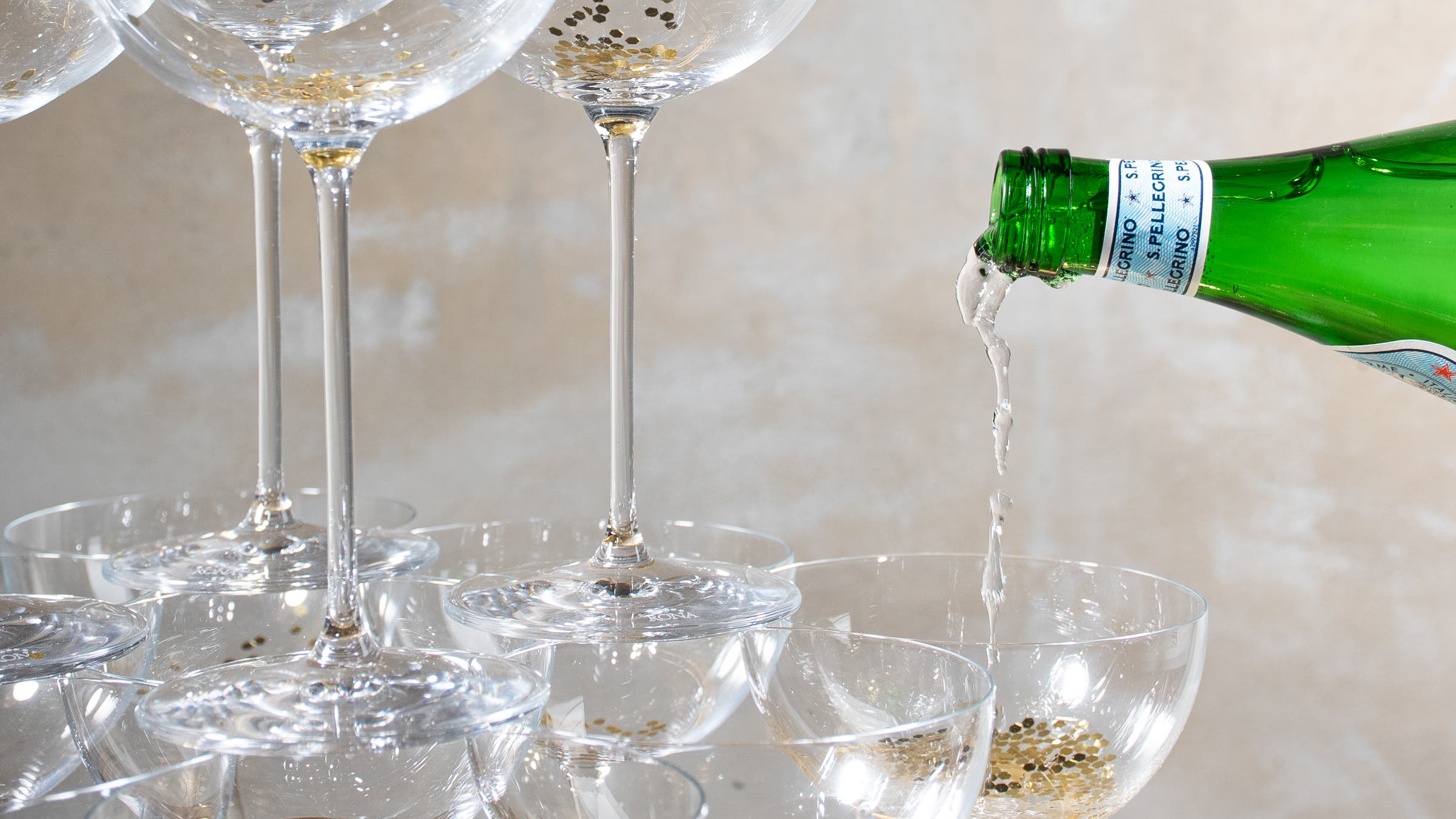 Sparkling water being poured into champagne glasses to represent the benefits of Dry January