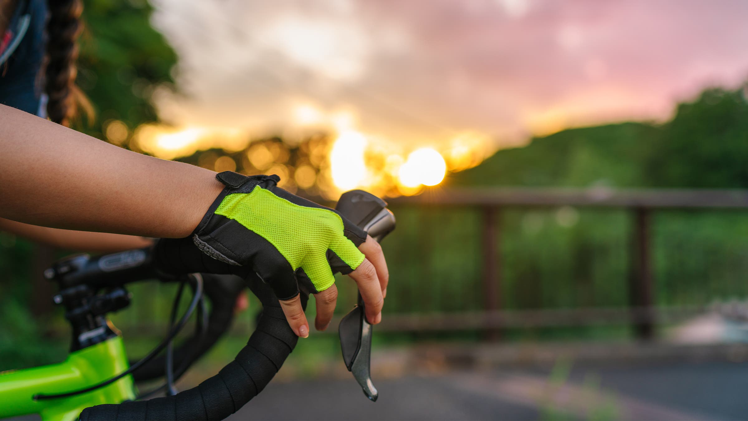 Shot of gloved hands on a road bike's handlebars with sunset in background