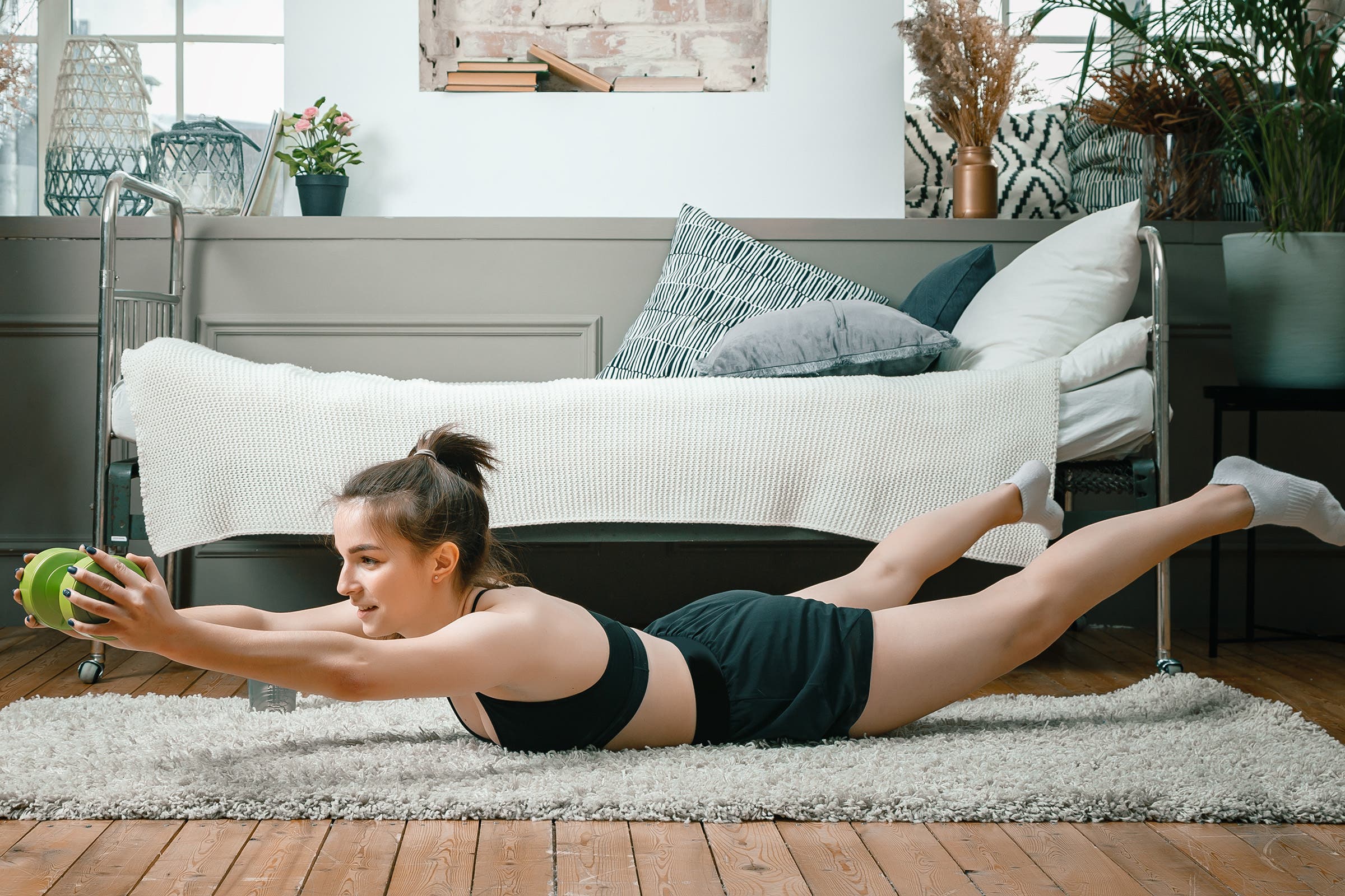 woman doing superman pose with a weight, one of the best exercises for lower back pain