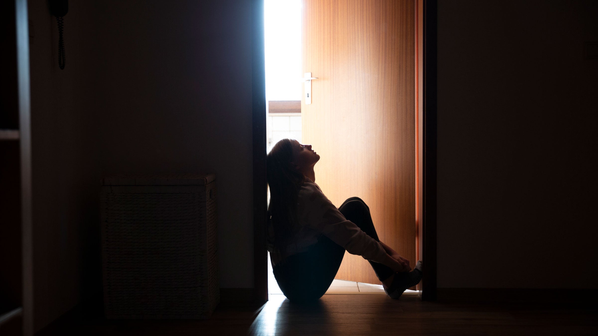 Stressed person sits against a wall
