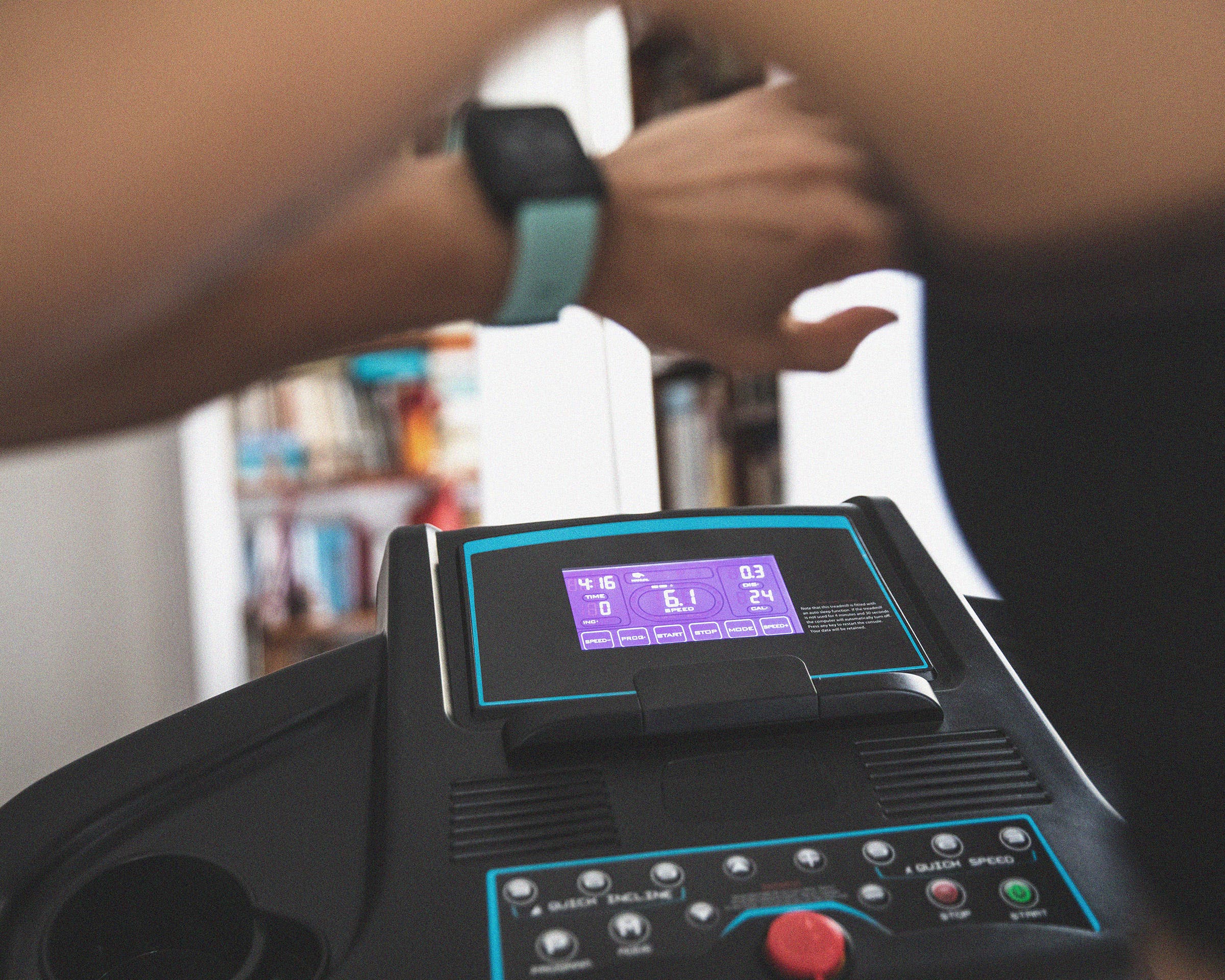 woman checking her pace on her watch while running on a treadmill