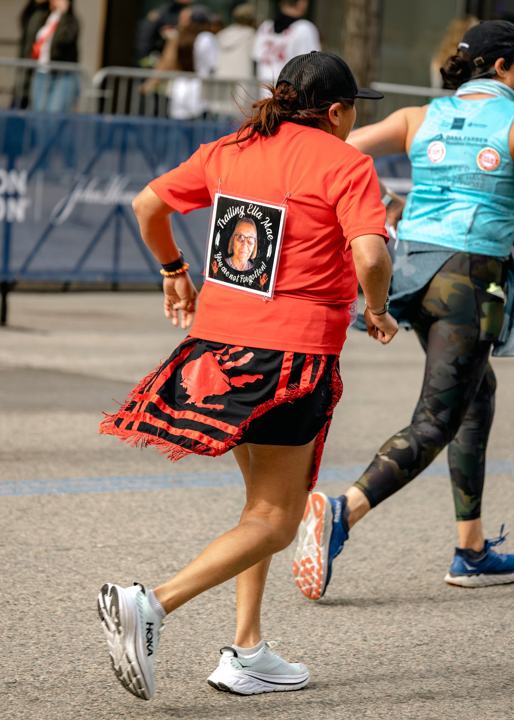 Verna Volker running the Boston marathon with a kit representing missing and murdered indigenous women