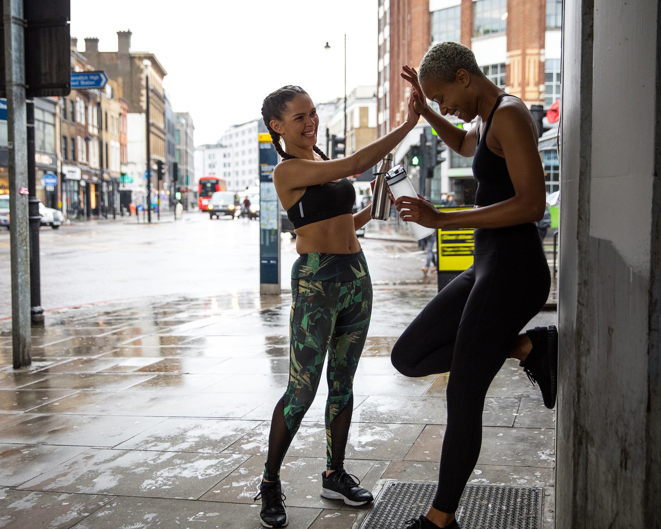 women high-fiving after a run in rainy London