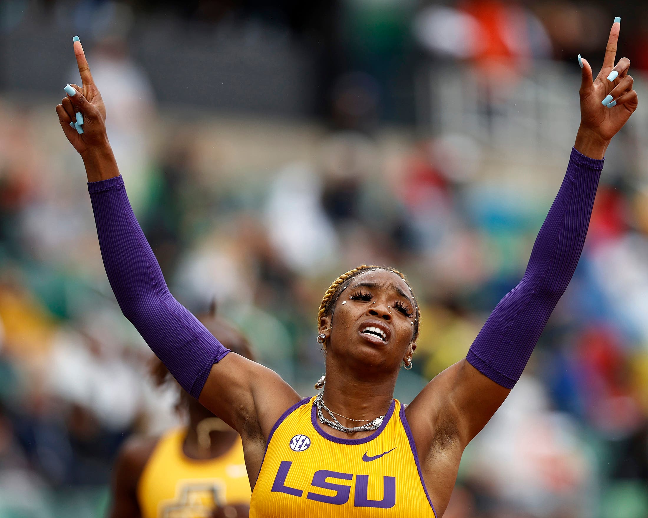Alia Armstrong in an LSU kit with her hands raised after winning