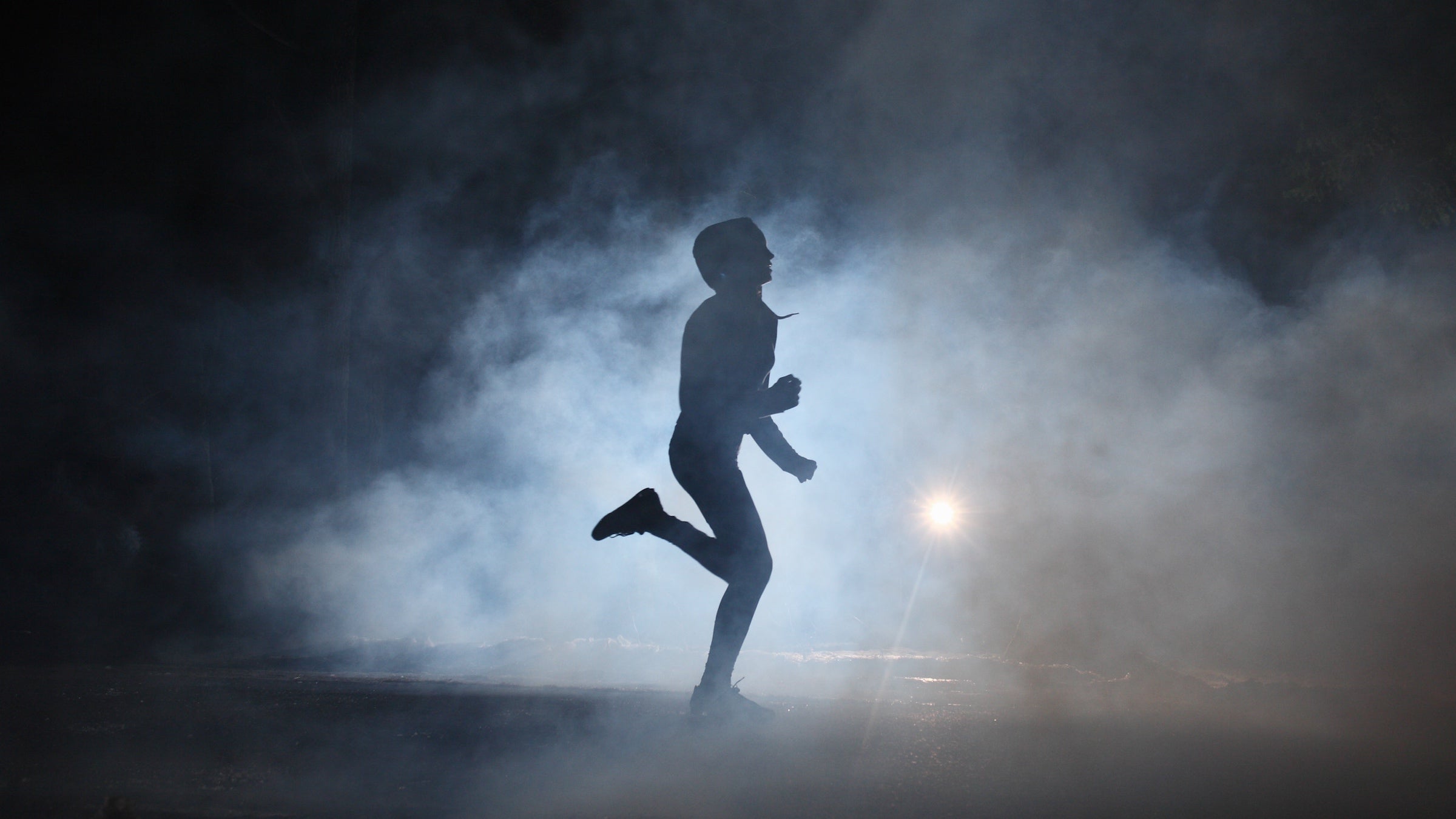 A hooded runner trains at night.