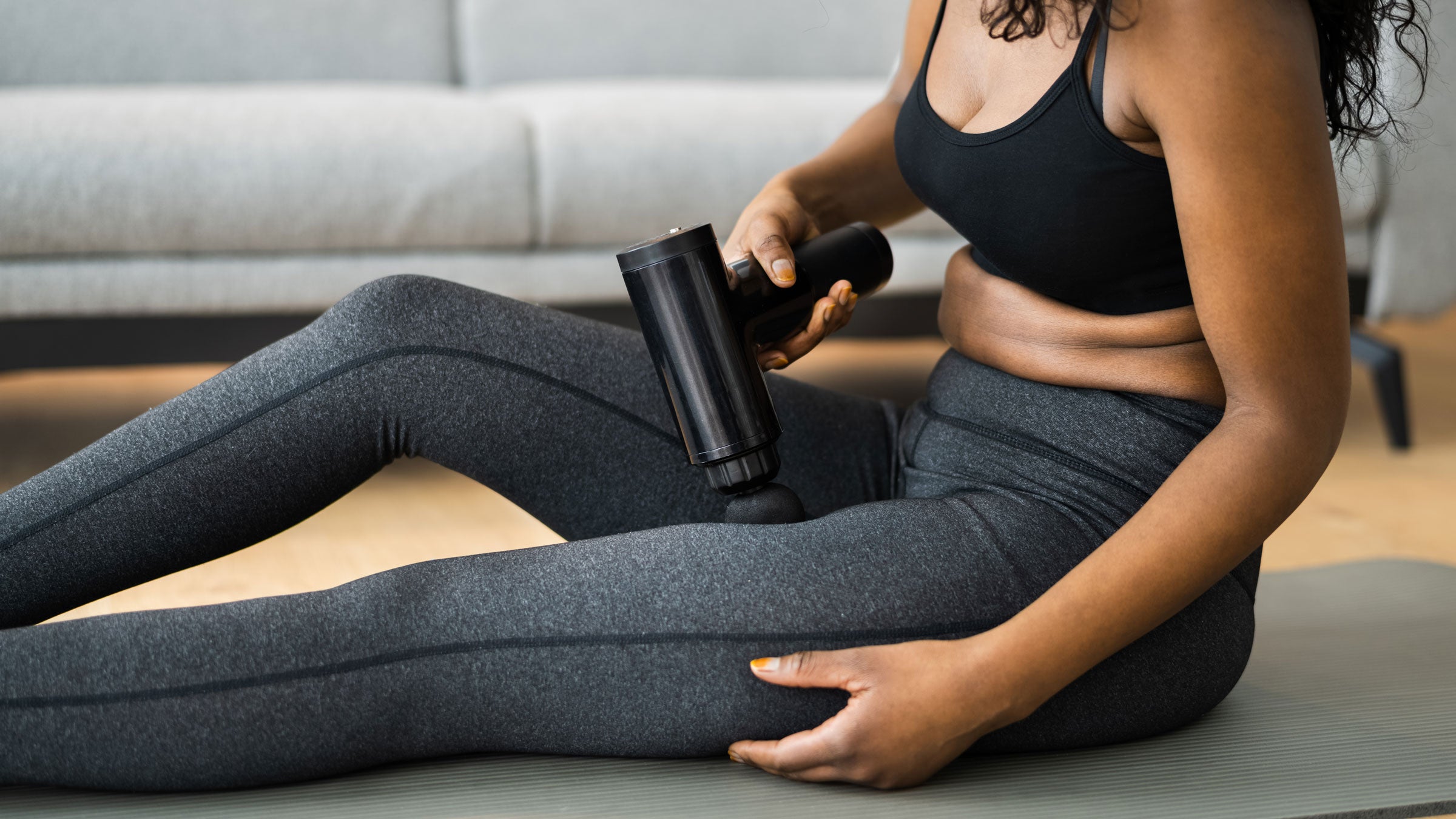 Woman uses a massage gun on her legs