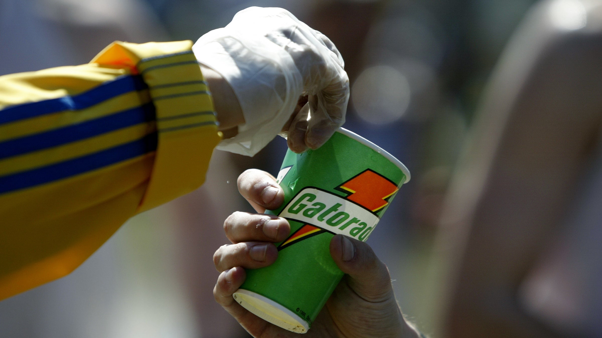 A detail shot of a volunteer as he hads a Gatorade refreshment cup to a runner as he passes through a water station in the town of Natick during the Boston Marathon